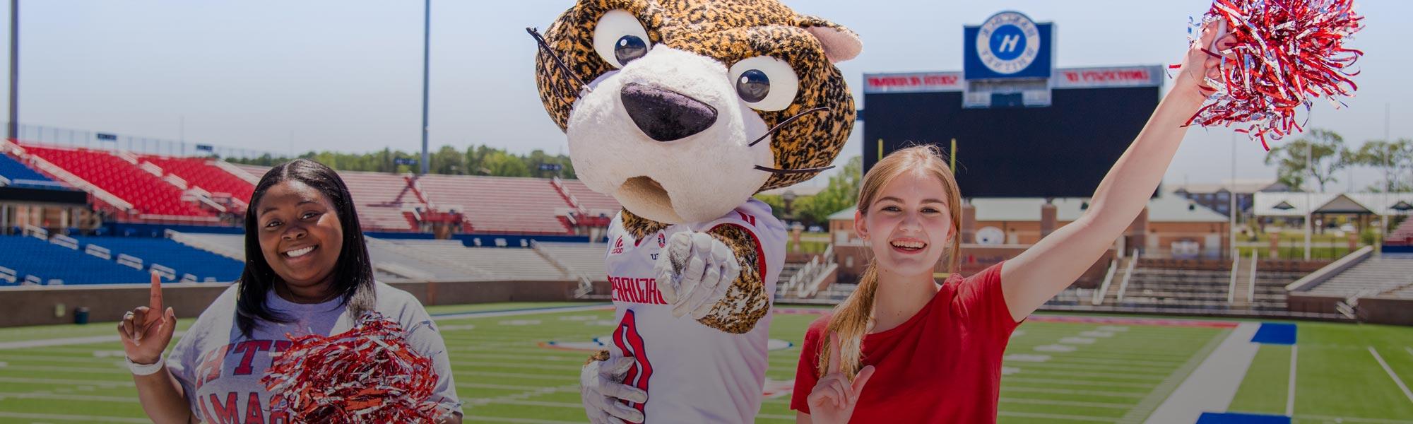Two female students with South Paw in Hancock Whitney Stadium